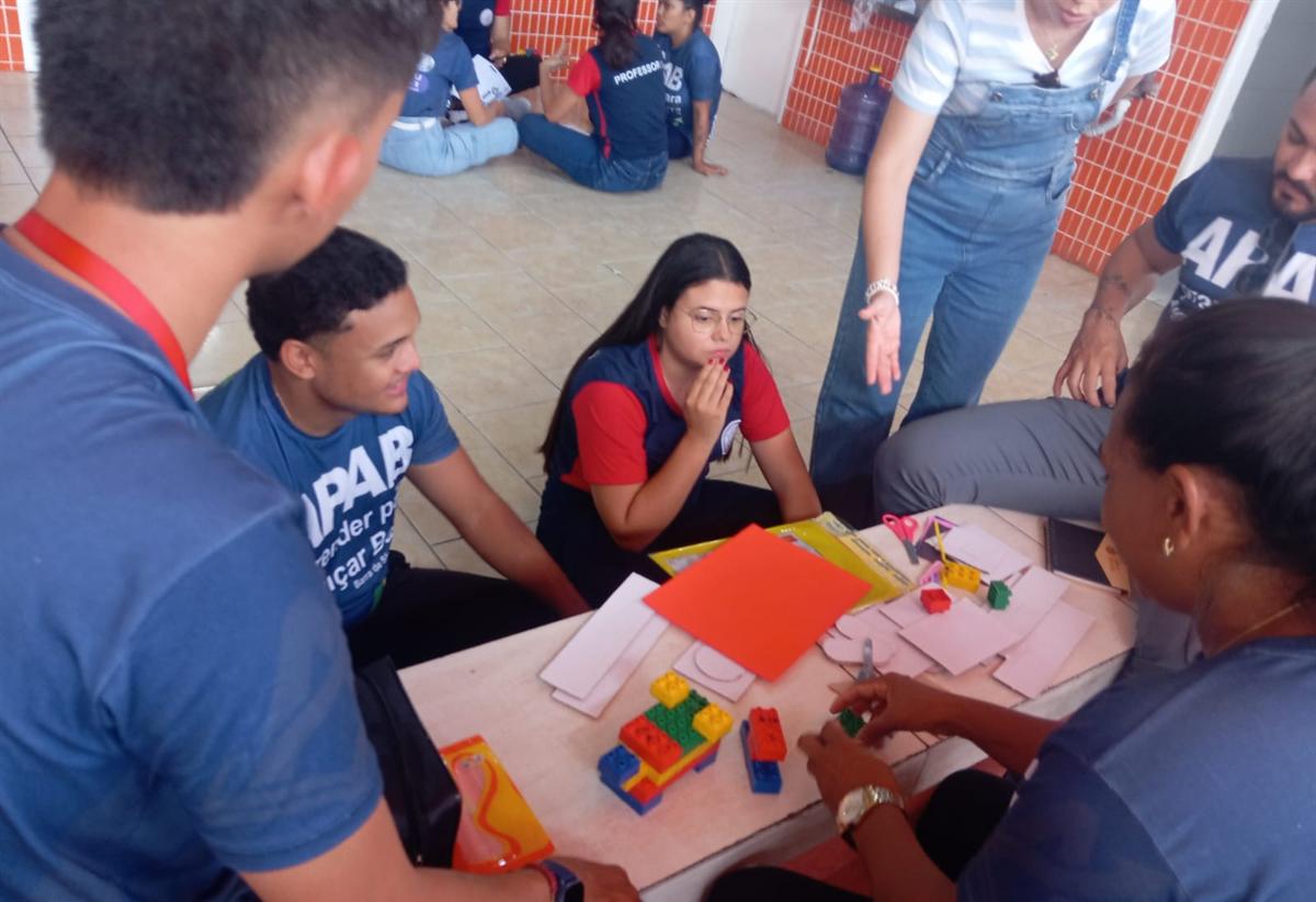Professores montam uma atividade com blocos coloridos sobre a mesa