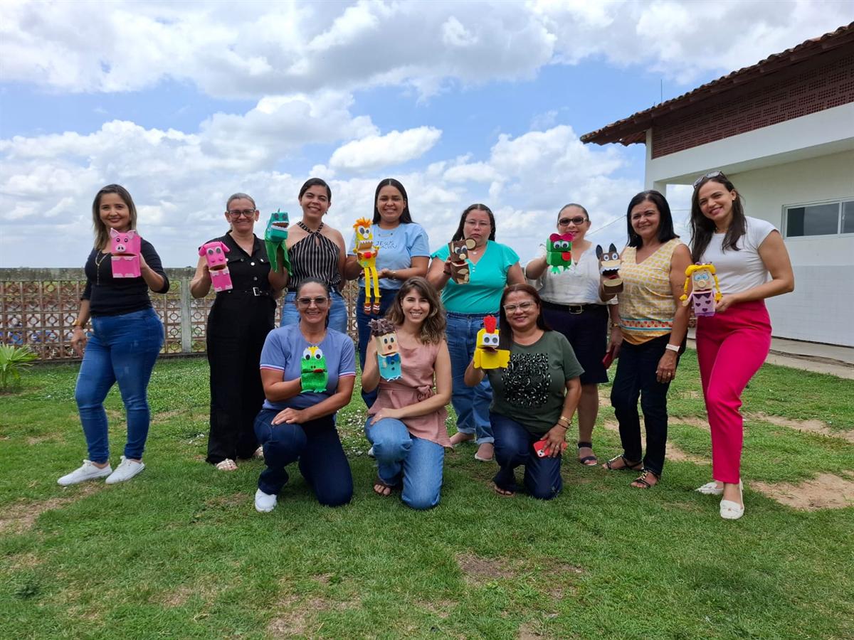 Professoras posam ao ar livre segurando fantoches