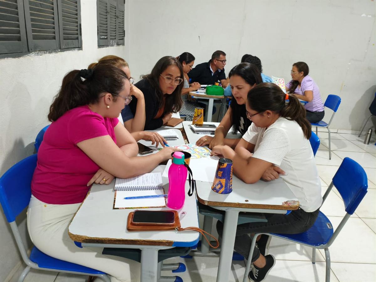 Professoras trabalham em grupos nas carteiras durante a formação