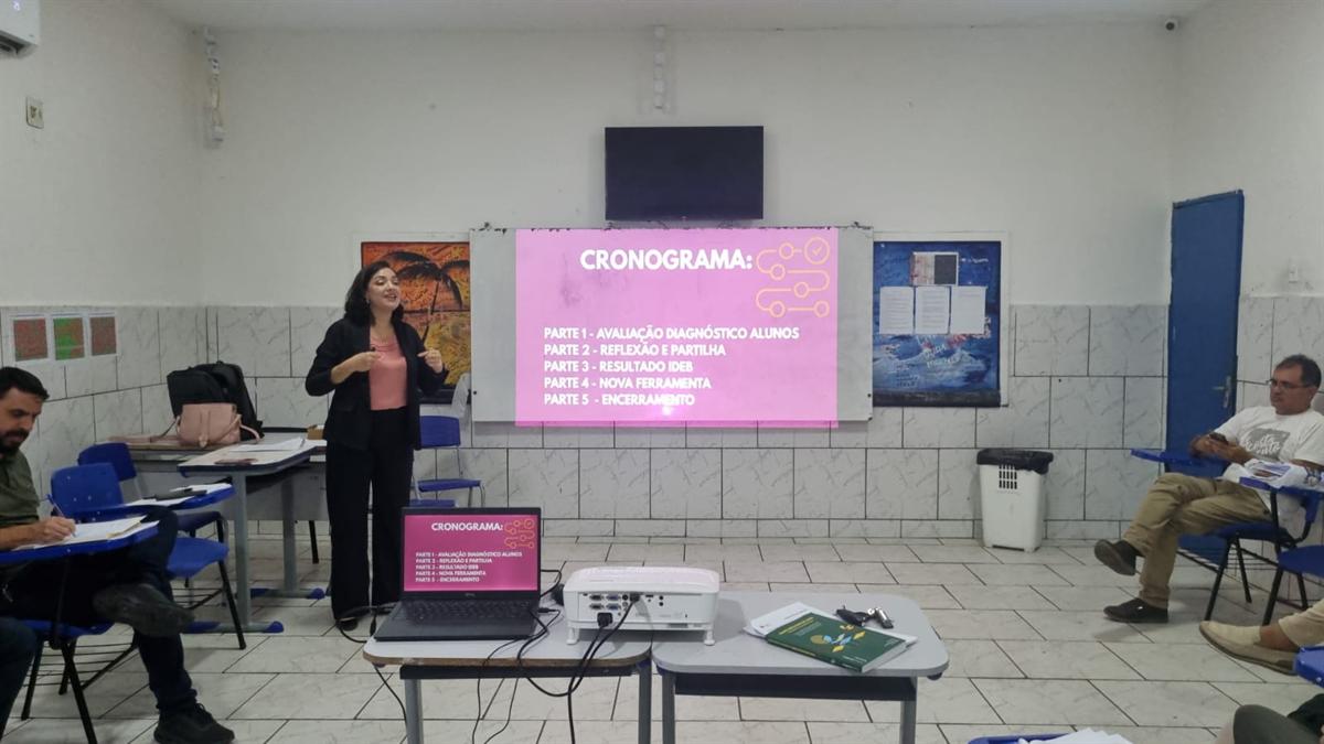 Apresentação com projetor para professores e gestores sentados em sala de aula